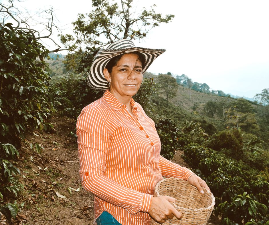 Caficultora colombiana con su canasta de recolección en la finca